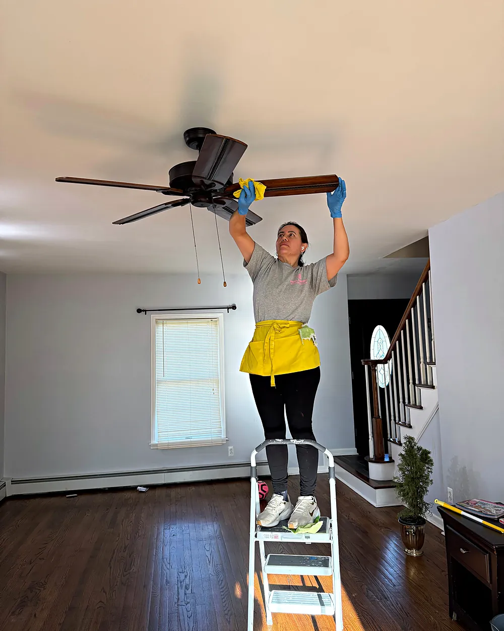 Cleaner dusting a ceiling fan, house cleaning in Rockaway, NJ