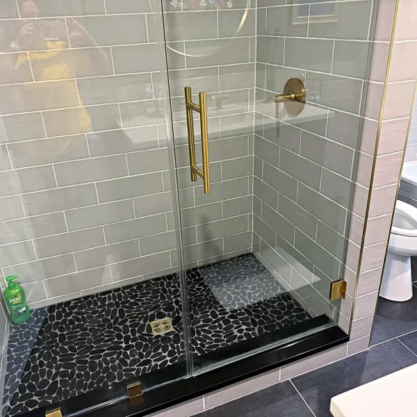 Spotless walk-in glass shower with gold fixtures after a bathroom cleaning